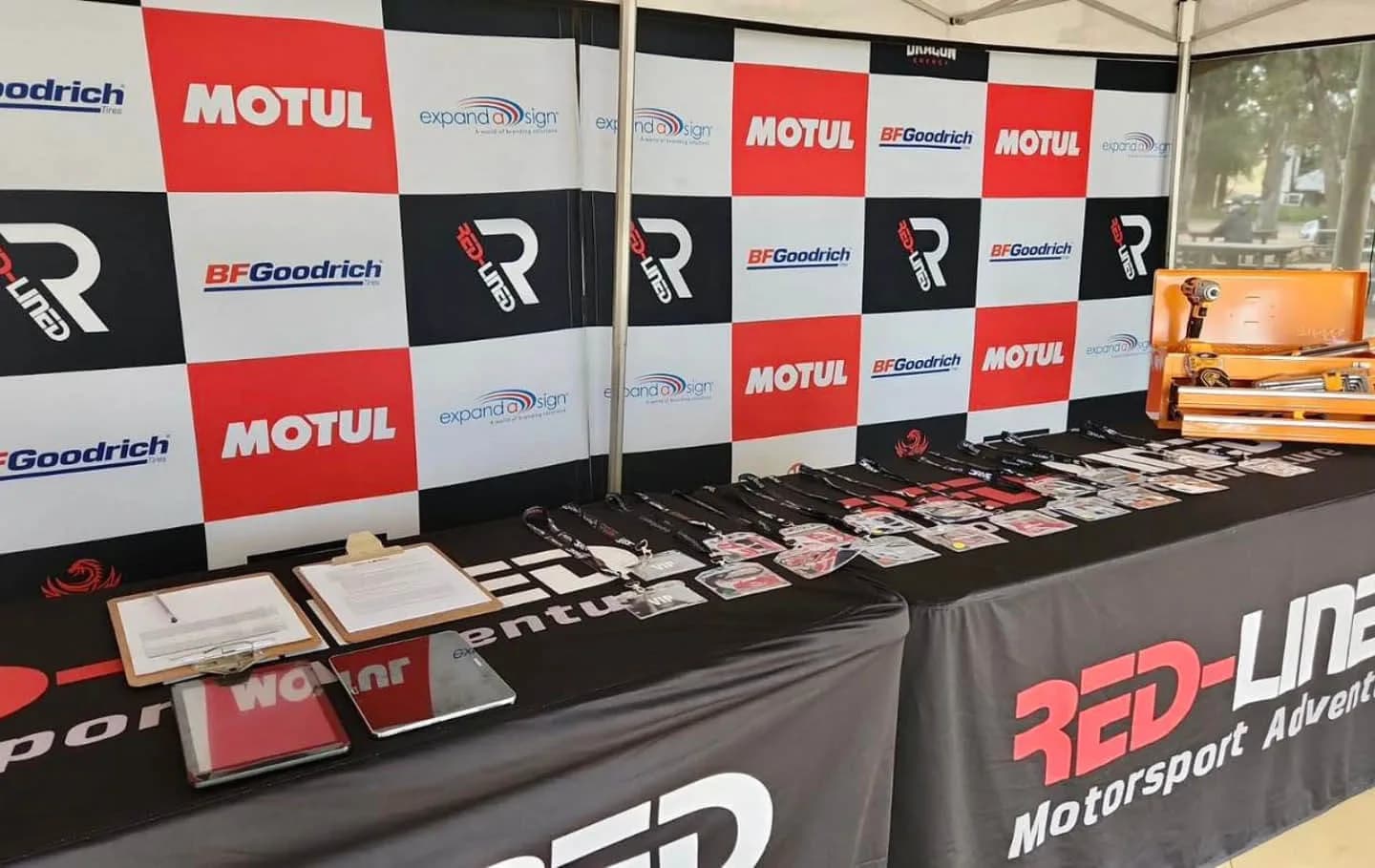 VIP passes laid out on the Red-Lined accreditation table under a branded gazebo